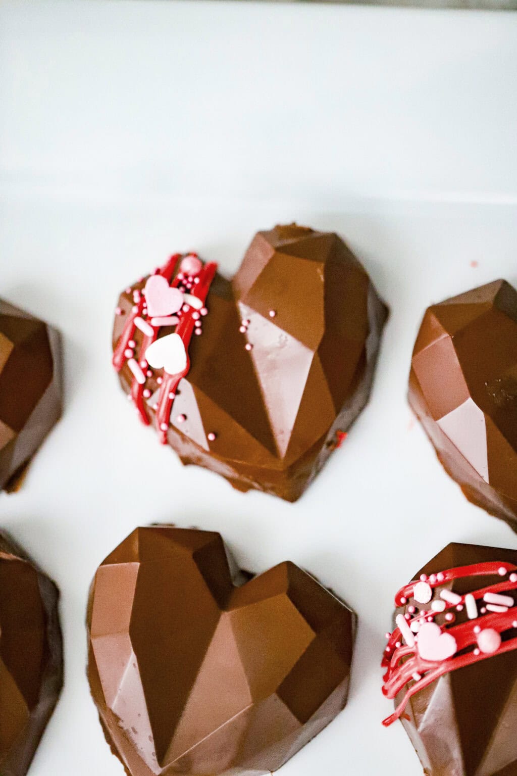 Homemade peanut butter cup hearts with silicone molds in the background